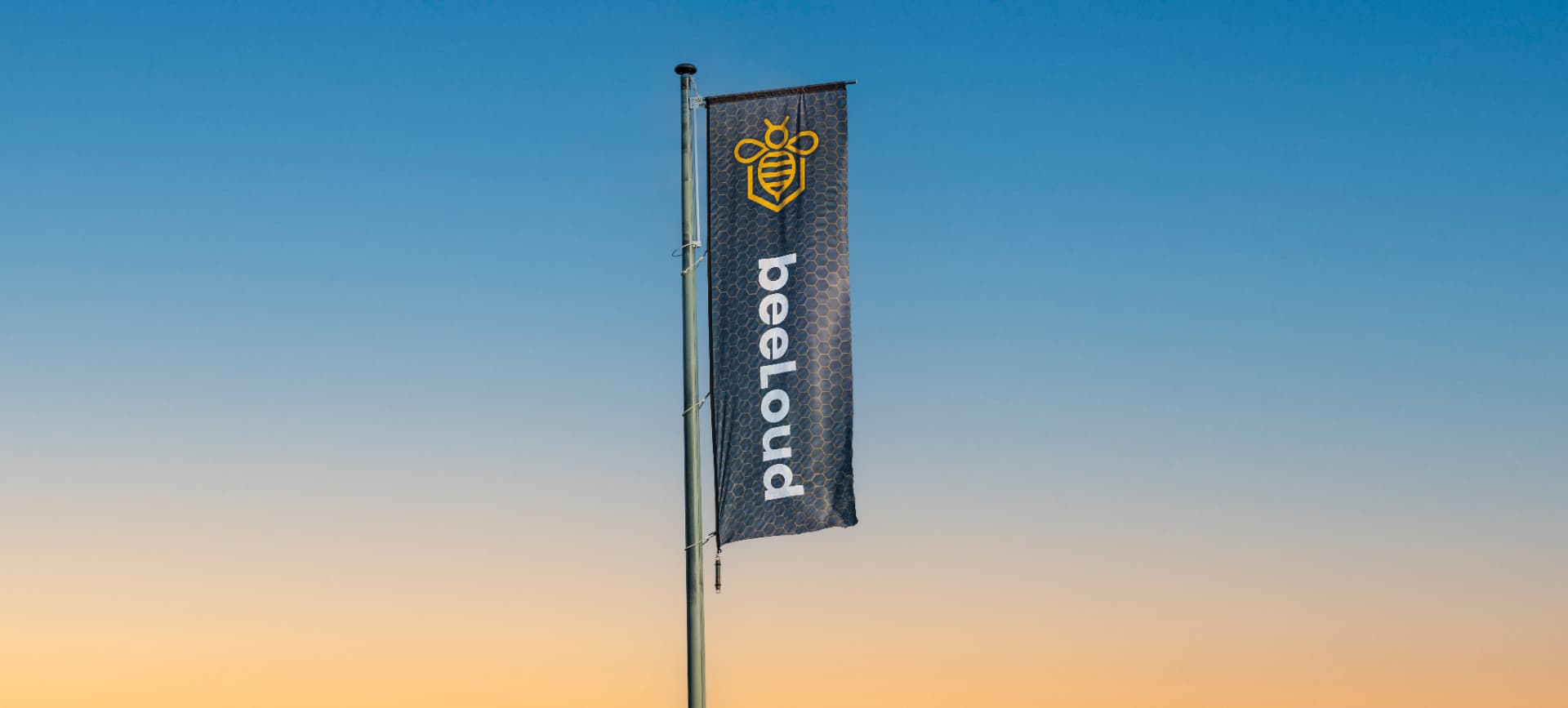 beeLoud-vlag aan een mast tegen een schemerlucht boven Texel